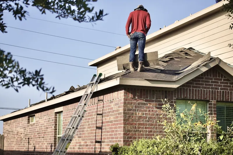 Professional roofer working on a residential roof in Evergreen Farms